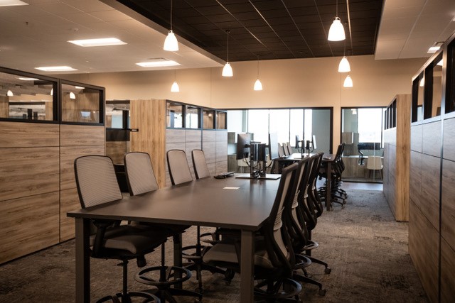 An office setting with a long, tall table and chairs on both sides.